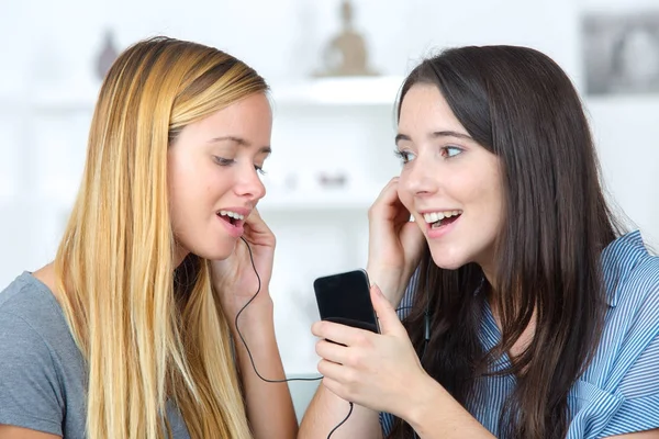 Två unga flickan lyssnar på musik med en smartphone — Stockfoto