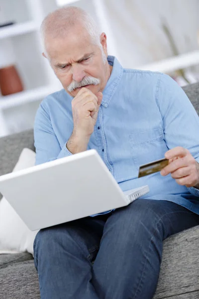 Senior man kopen op internet bezorgd over piraterij — Stockfoto