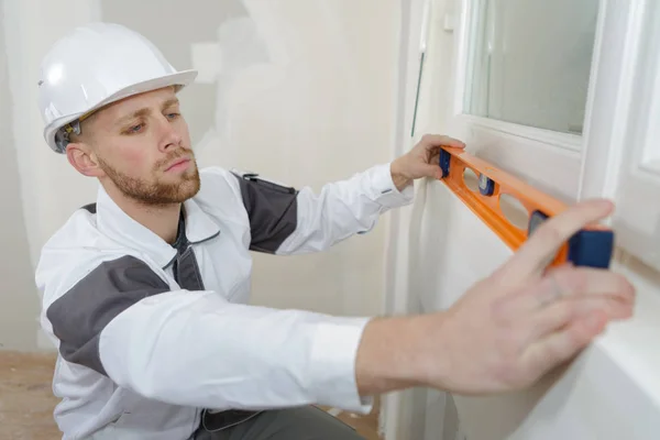 Uomo che utilizza livello spirito in una nuova casa — Foto Stock