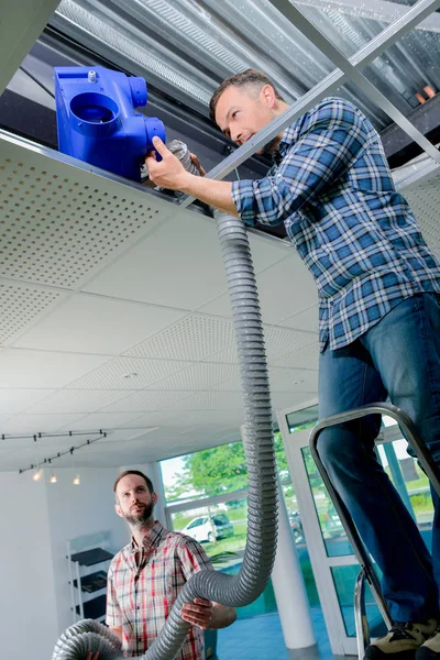 Due elettricisti che lavorano in un pannello a soffitto — Foto Stock