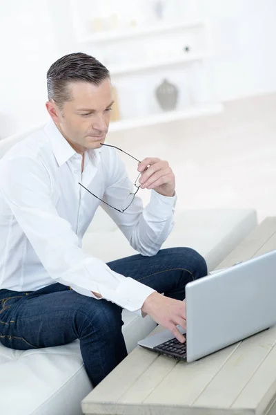 Uomo lavora per laptop sul divano — Foto Stock