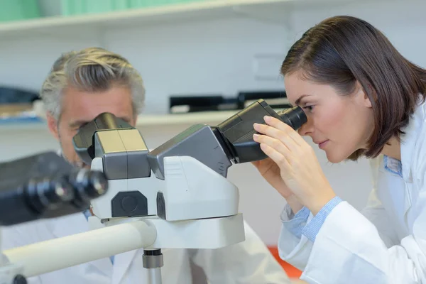 Samice technik dívá do mikroskopu — Stock fotografie