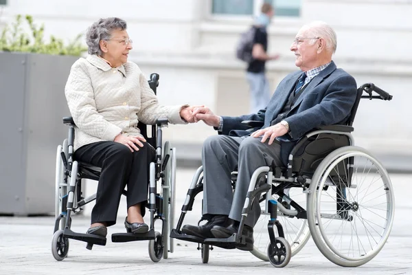 Casal velho na cadeira de rodas de mãos dadas — Fotografia de Stock