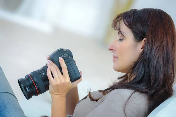 Mujer mirando a través de las fotos en la cámara — Foto de Stock