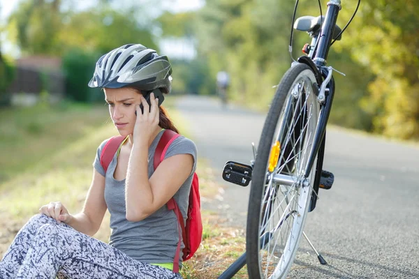 Mulher tentando corrigir problema de bicicleta chamando um amigo — Fotografia de Stock