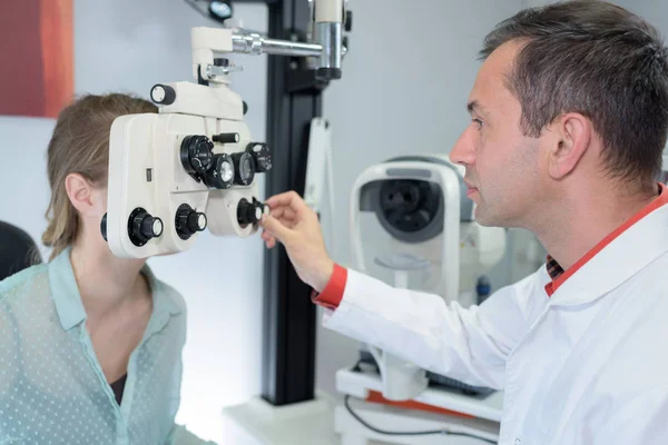 Optometrista ajustando o equipamento durante a consulta — Fotografia de Stock
