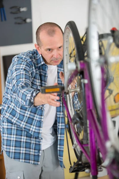 Mecânico serviceman ajustando bicicleta em sua oficina — Fotografia de Stock