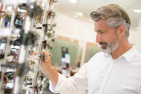 El hombre que se prueba las gafas a los optometristas sonriendo — Foto de Stock