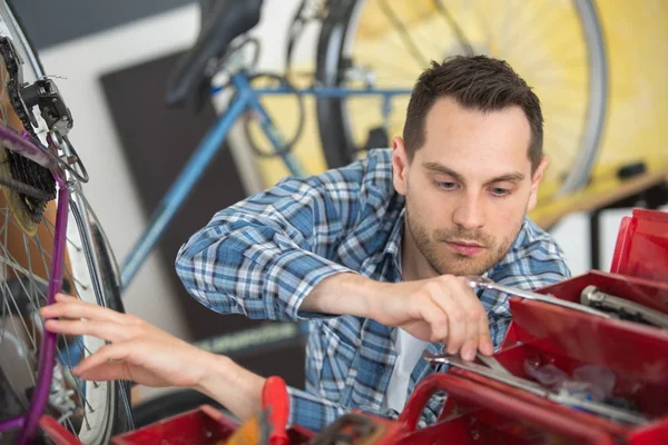 Концентрированный человек ремонтирует велосипедное снаряжение в своей мастерской — стоковое фото