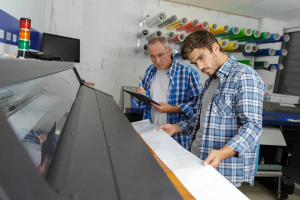 Dos hombres mirando hacia abajo a la impresora profesional —  Fotos de Stock