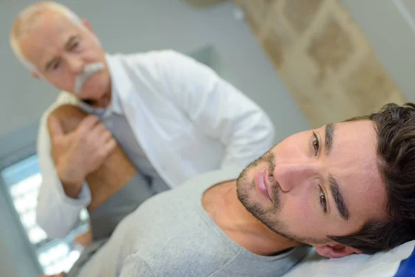 Physiothérapeute travaillant avec un jeune patient faisant des exercices de mobilité — Photo