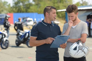 young man with instructor during motorbike lesson clipart