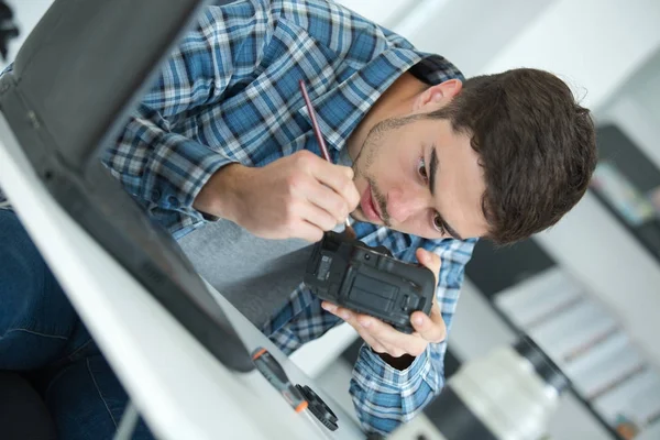 Jeune beau technicien examinant et réparant la caméra dslr — Photo