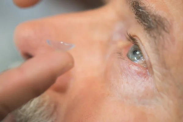 Man putting contact lens in his eye — Stock Photo, Image