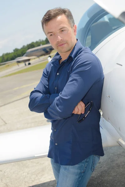 Retrato de piloto joven adulto fresco sentado contra avión privado —  Fotos de Stock