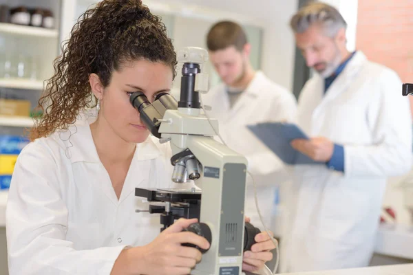 Νεαρή γυναίκα ιατρικός ερευνητής ψάχνει μέσω microscop — Φωτογραφία Αρχείου