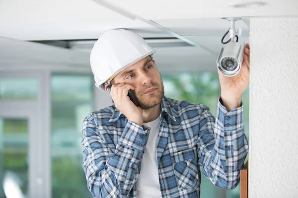 Técnico de cctv profissional masculino usando o telefone enquanto trabalhava — Fotografia de Stock