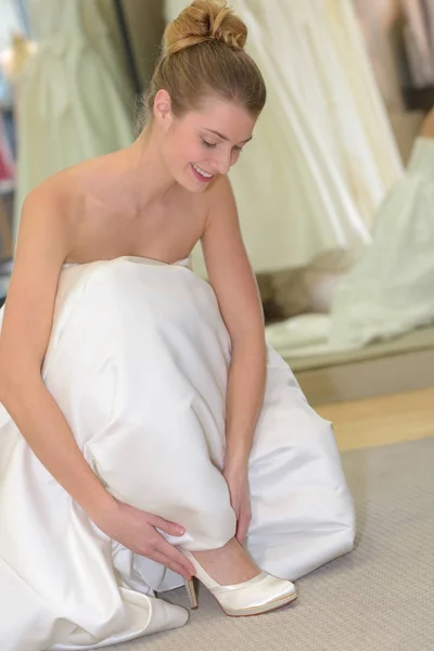 Donna in abito da sposa cercando su scarpe — Foto Stock