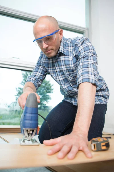 Carpenter cutting laminated planks for layered parquet using bandsaw — Stock Photo, Image