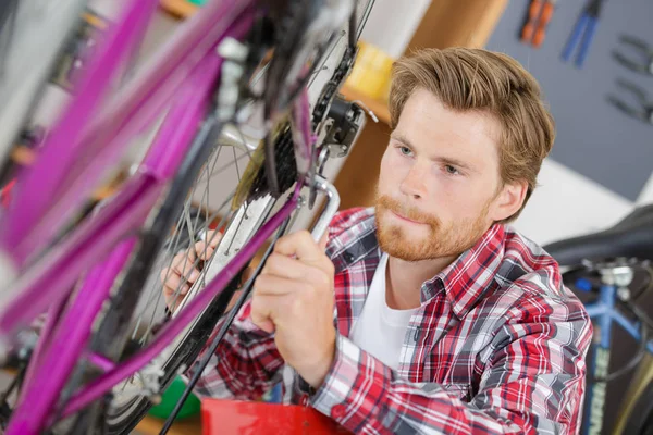 Mecânico de bicicletas elegante fazendo seu trabalho profissional na oficina — Fotografia de Stock