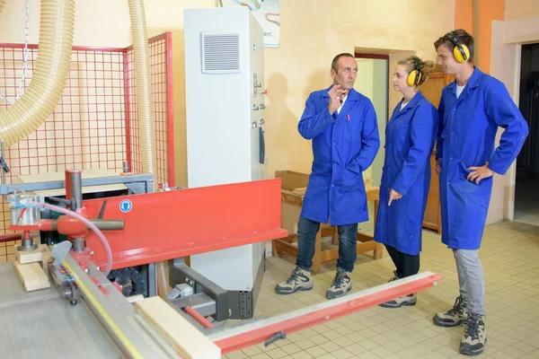 Apprentices wearing ear protectors observing machinery — Stock Photo, Image