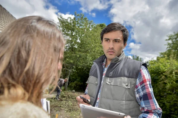 Jardinier conversant avec le client, tenant la tablette — Photo