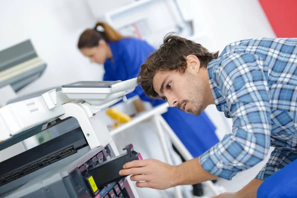 Людина технік ремонтує принтер на робочому місці — стокове фото