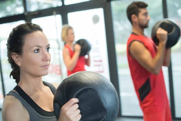 Pessoas que trabalham com kettle bell em um ginásio — Fotografia de Stock