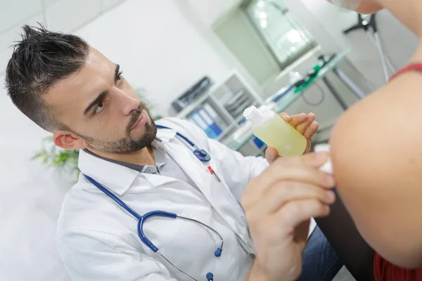 Young doctor rubbing alcohol on patient's skin — Stock Photo, Image