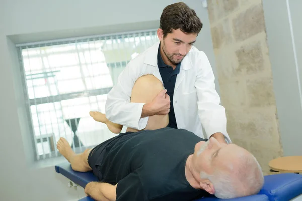 Physiotherapeutin arbeitet an Bein männlicher Patienten — Stockfoto