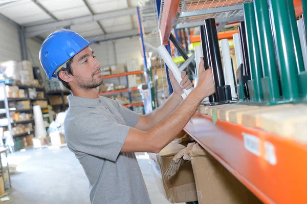 Trabalhador levando itens de metal da prateleira — Fotografia de Stock