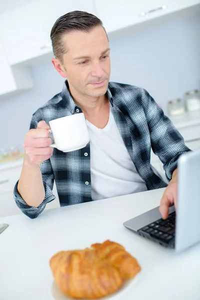 घर पर लैपटॉप का उपयोग करते समय आदमी कॉफी पी रहा है — स्टॉक फ़ोटो, इमेज