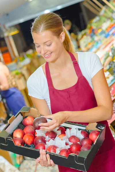 Assistente al negozio che guarda le pesche noci in vassoio — Foto Stock