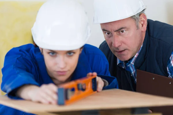 Portrait of female builder with spirit level and teacher — Stock Photo, Image