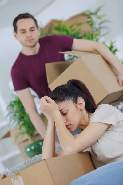 Casal cansado sentado entre caixas de papelão — Fotografia de Stock