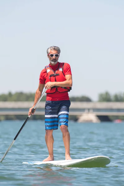 Hombre disfrutando de un paseo en el lago con paddleboard —  Fotos de Stock