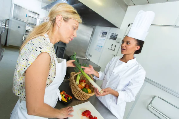Positieve vrouwelijke chef-koks poseren met plaat van salade en kaas — Stockfoto