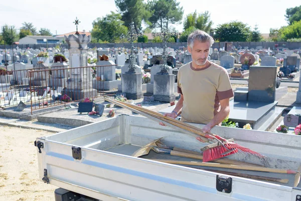 Człowiek konserwacji cmentarza ładowanie narzędzia do przyczepy — Zdjęcie stockowe