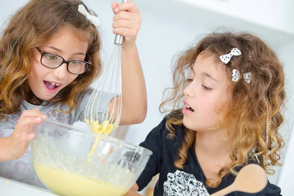 Zwei junge Mädchen, die allein auf einem Kuchen backen — Stockfoto