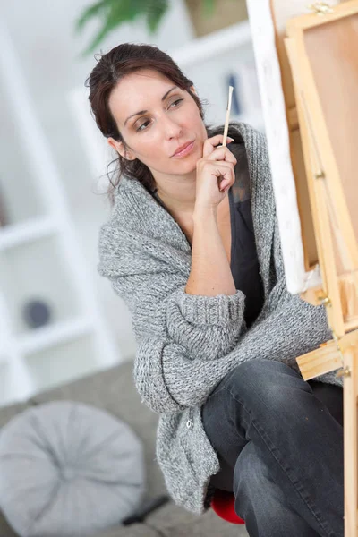 Doordachte vrouw schilder denken in atelier van de kunstenaar — Stockfoto