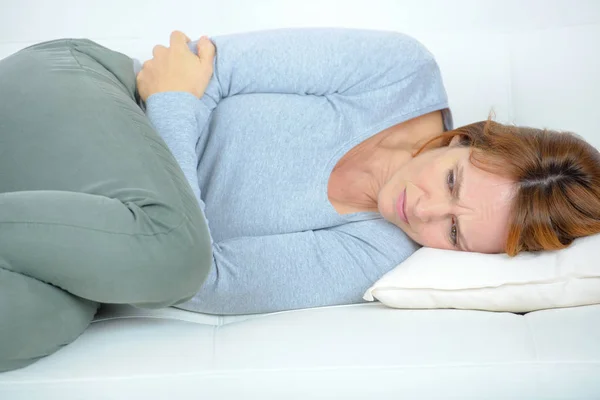 Femme dans la douleur sur son canapé — Photo