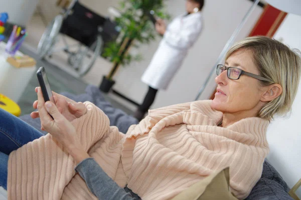 Frau benutzt Handy beim Warten im Krankenhaus — Stockfoto