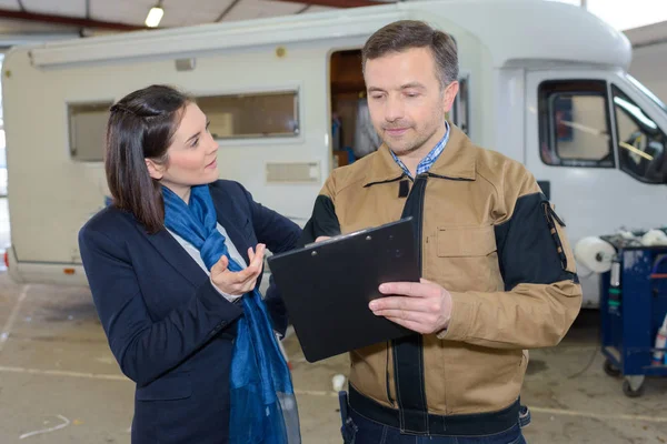 Signora parlando con garage lavoratore holding appunti — Foto Stock