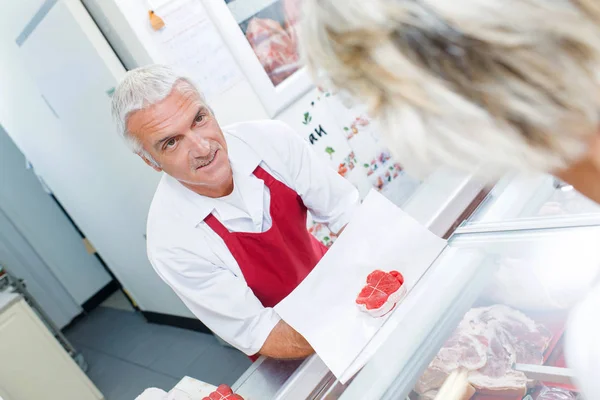 Macellaio che mostra carne al cliente — Foto Stock