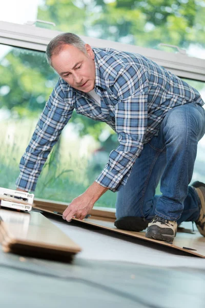 Reifer Handwerker verlegt Holzboden im Gebäude — Stockfoto