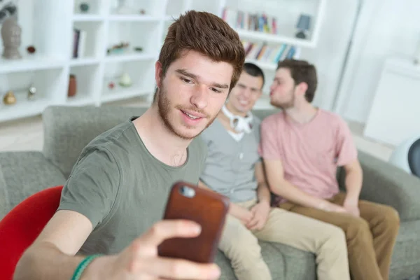 Nastoletni chłopak uśmiechając się i robić selfie na smartfonie w domu — Zdjęcie stockowe