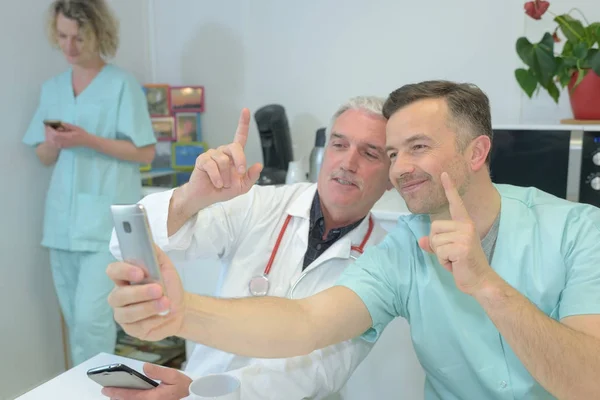 Usmívající se tým lékařů a sester v nemocnici s selfie — Stock fotografie