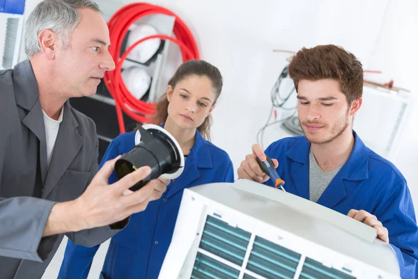 Profesor observando a los estudiantes que trabajan en aparatos eléctricos — Foto de Stock