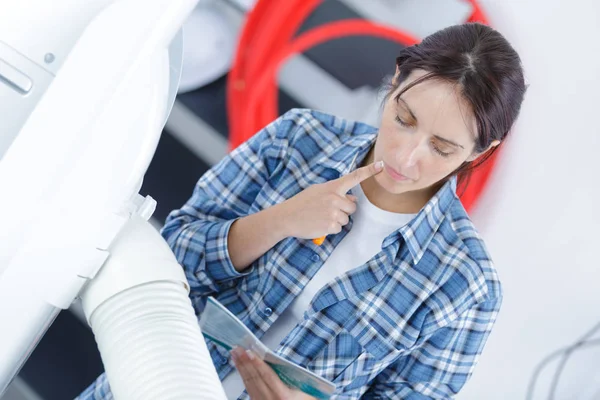 Fontanero femenino examinando los tubos de la caldera de calefacción central —  Fotos de Stock