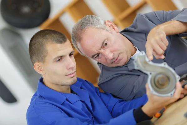 Apprentice mechanic and mentor analyzing broken part — Stock Photo, Image